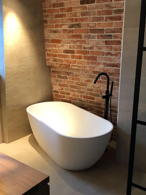 Badkamer in Aerdenhout met vrijstaand bad en bakstenen wand
