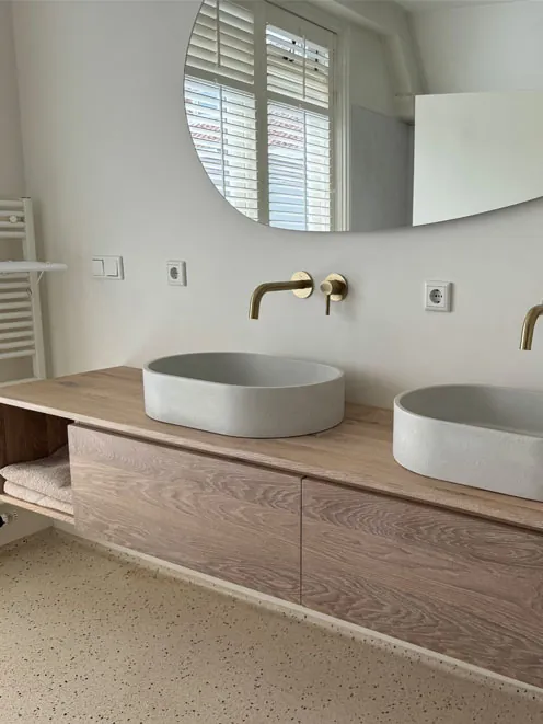 Badkamer in Haarlem met dubbele waskom en ronde spiegel